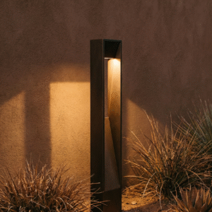 Modern outdoor garden lamp with warm white light illuminating a pathway, surrounded by plants and textured wall