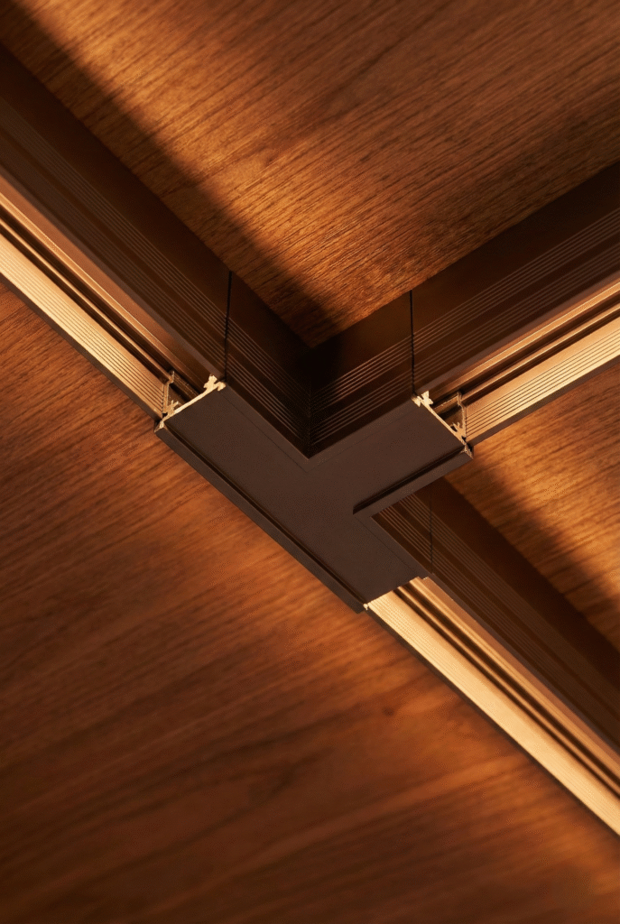 Metal track lighting connectors installed on wooden ceiling surface