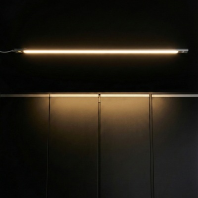 Slim LED cabinet light bar installed under shelf with warm illumination